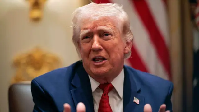 President Donald Trump speaking during a cabinet meeting. His hands are gestured outward and he is mid speech