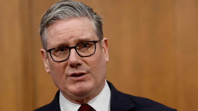 UK Prime Minister Keir Starmer, a man with short, grey hair, glasses and a dark suit.