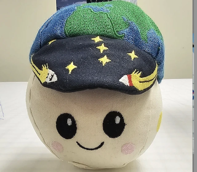 a plush Moon in a cap embroidered with stars and a tiny Earth