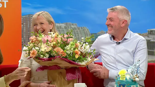 Steve and Carol on the sofa with flowers