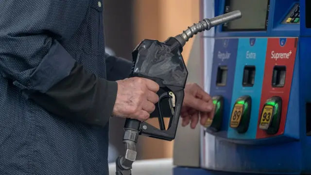 A driver refuels a vehicle with unleaded petrol at a gas station in New York