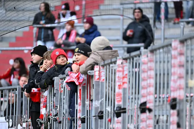 Fans stand at the front of the terace watching the warm up
