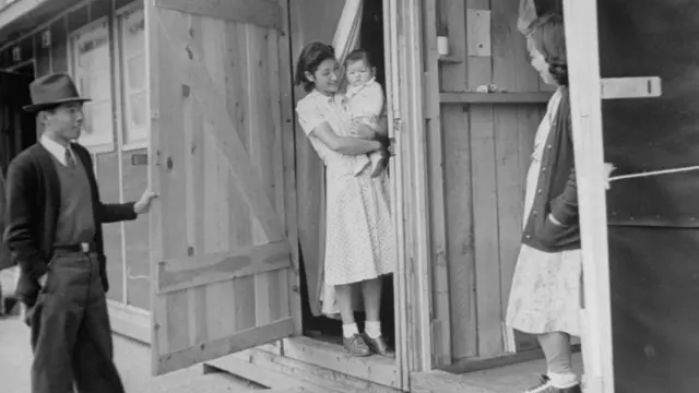 Японская семья стоит возле своего жилого помещения в лагере для интернированных в США, 1942 год.