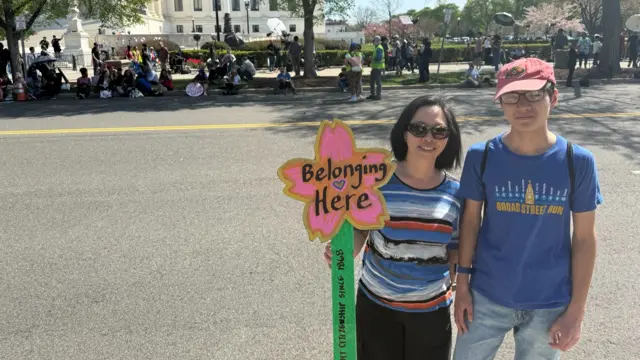 Ханна Ким и Дэниел Ошоа стоят возле Верховного суда. Ким держит табличку в форме цветка