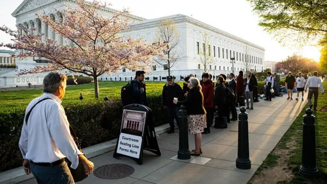 People queue behind a sign that reads "Courtroom seating line forms here"