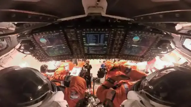 An image of two crew members at the controls in the capsule