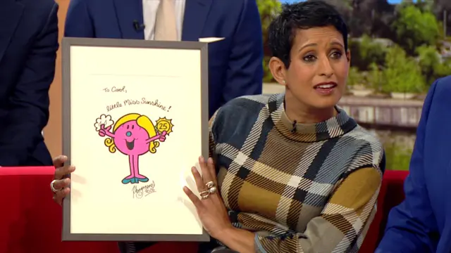 Naga Munchetty holding a Little Miss Sunshine poster.