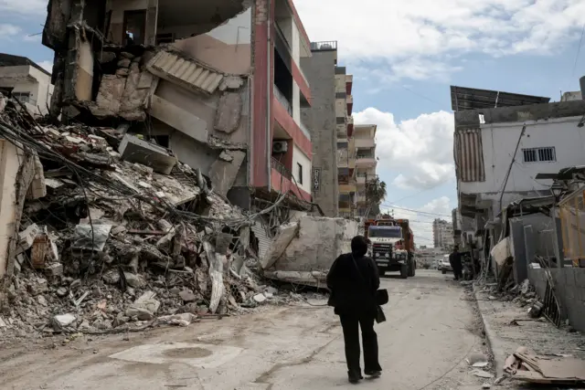 A silhouetted figure walks past a building damaged by air strikes in Tyre on Friday.