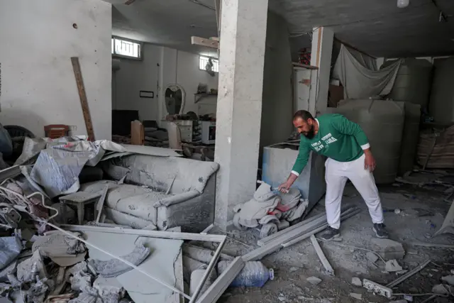 An indoor shot shows a man moving debris inside a damaged building in Tyre on Friday