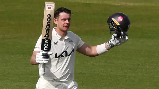 Jamie Smith raises his bat after getting 100