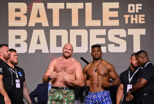 Tyson Fury and Francis Ngannou stand side-by-side and hold up their fists