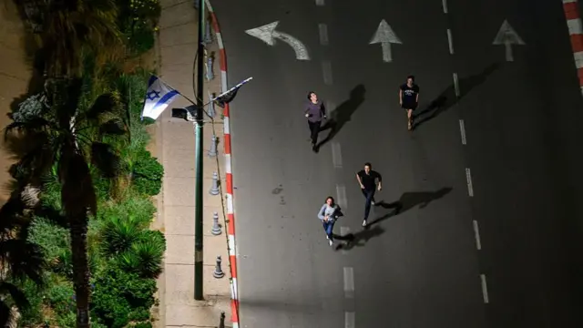 People run to take shelter as sirens sound during incoming missile fire, without an early warning, allegedly from Hezbollah, just after midnight on the third day of the U.S. Israel Iran Ceasefire on April 10, 2026 in Tel Aviv, Israel.