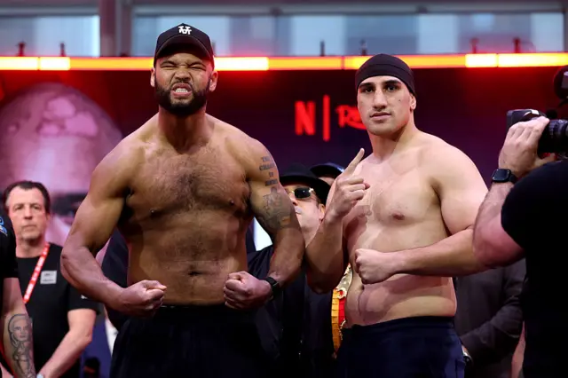 Frazer Clarke flexes his muscles alongside Justis Huni at a weigh-in