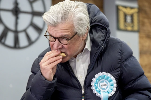 Malcolm Offord eating a Scotch pie in a cafe