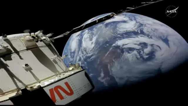 The Orion spacecraft seen with the Earth in the background. Swirls of clouds can be seen on the planet, with the bottom half hidden in darkness