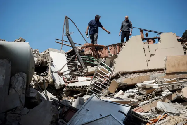Two people stand atop rubble and debris where a building once stood in Tyre on Friday