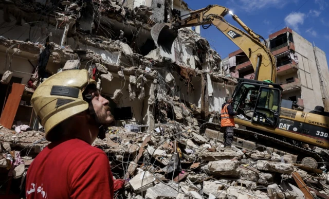 Rescuers assisted by heavy machinery work at the site of an Israeli strike carried out