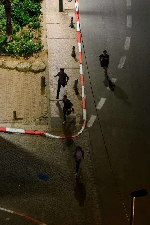 People run to take shelter as sirens sound during incoming missile fire, without an early warning, allegedly from Hezbollah, just after midnight on the third day of the U.S. Israel Iran Ceasefire on April 10, 2026 in Tel Aviv, Israel.