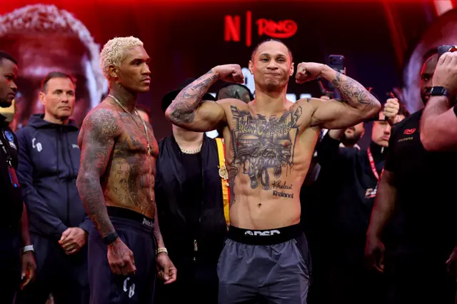 Conor Benn stares at Regis Prograis as he flexes his muscles at a weigh-in