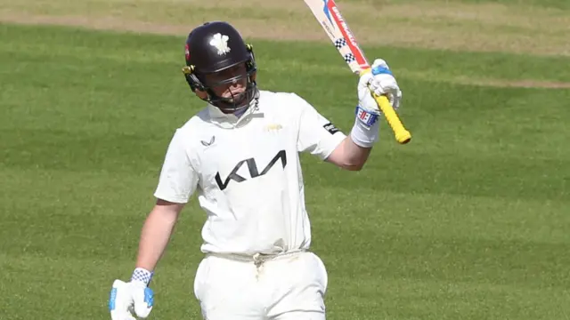 Surrey's Ollie Pope raises his bat after reaching 50
