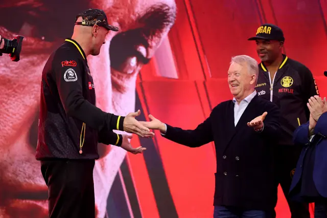 Tyson Fury and Frank Warren look at each other with their arms out