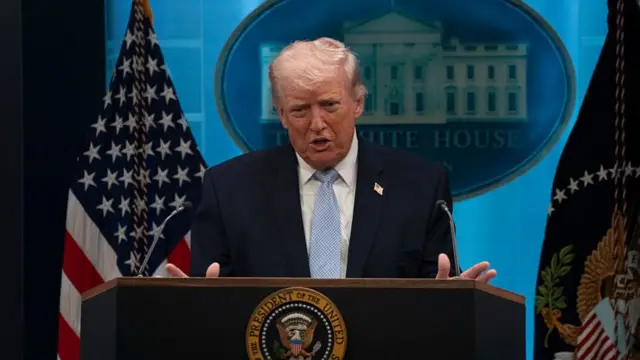 Trump at a lectern that has the President of the United states seal on the front of it speaking