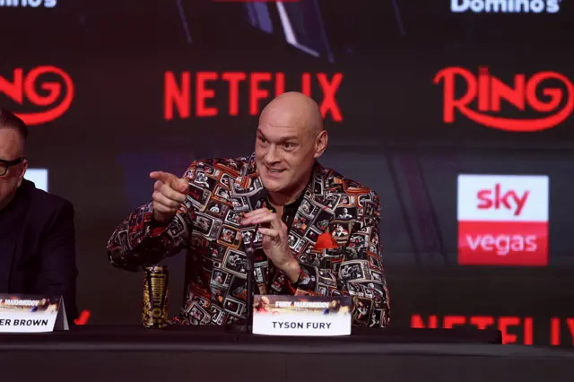 Tyson Fury holds a microphone and points