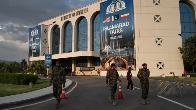 Pakistani security personnel stand outside a government building in Islamabad with banners that say 'Islamabad talks'.