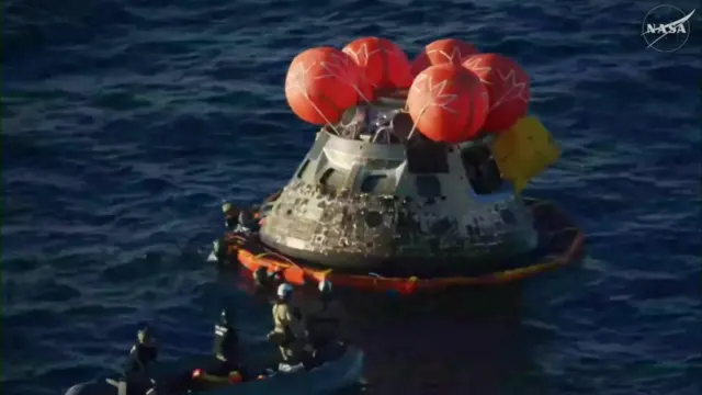 The stabilisation ring is secured to the Orion module, with various rescue personnel stationed around the spacecraft