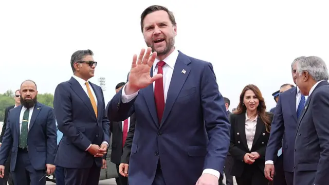 US Vice President JD Vance waves after arriving in Islamabad, with Pakistani officials behind him.