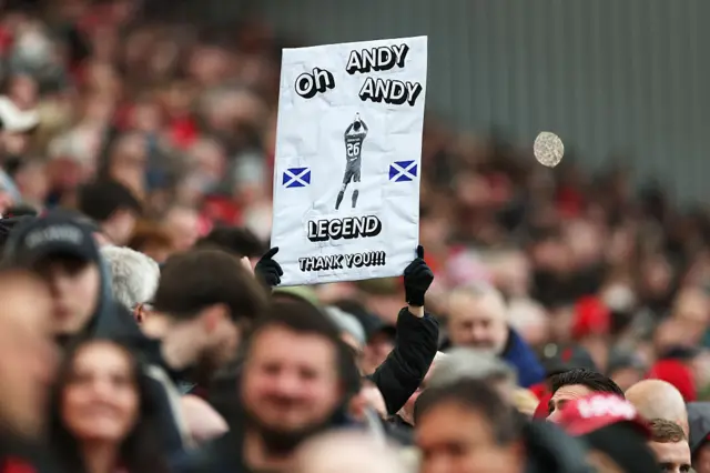 A fan of Liverpool displays a sign in support of Andrew Robertson reading "Oh Andy Andy Legend thank you"