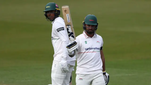 Jake Weatherald raises his bat after getting 50 for Leicestershire at Surrey and his opening partner Rishi Patel stands next to him