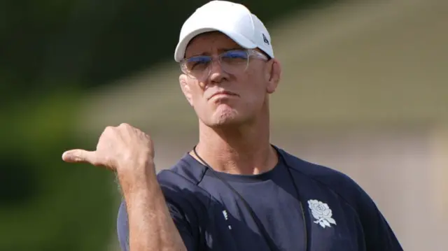 John Mitchell points with his thumb to the left