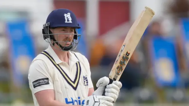 Left-handed Rob Yates holding his bat high in the air