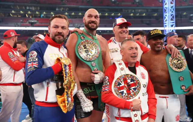Tyson fury holds the WBC heavyweight title and stands with his team