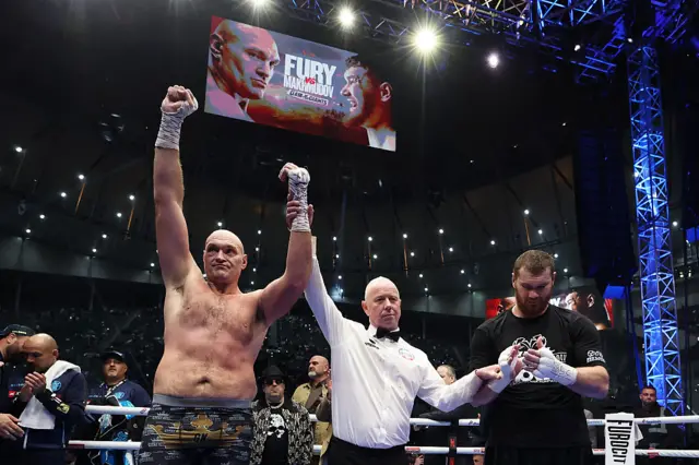 Tyson Fury has his arm raised next to Arslanbek Makhmudov