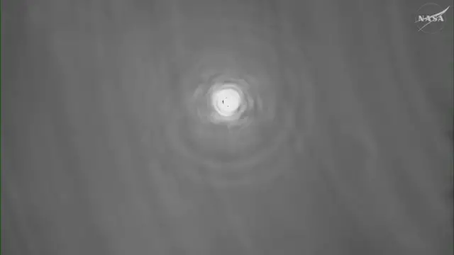 View of the Orion spacecraft as communications return, seen as a bright light in the middle of a dark grey background