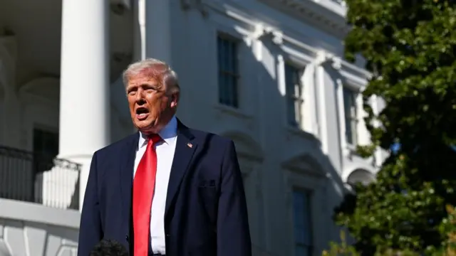 Donald Trump speaking to reporters at the White House on Saturday, he is wearing a dark suit and a red tie