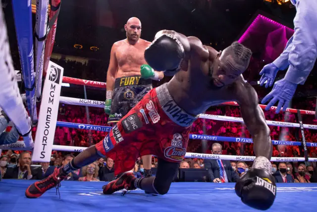 Deontay Wilder falls to the canvas with Tyson Fury in the background