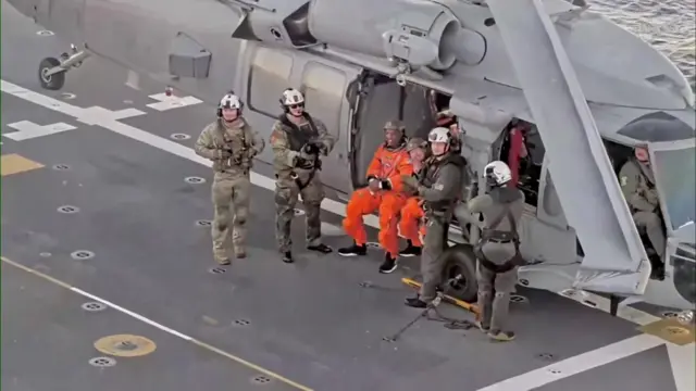 Christina Koch and Victor Glover sitting on the flight deck of the USS John P Murtha