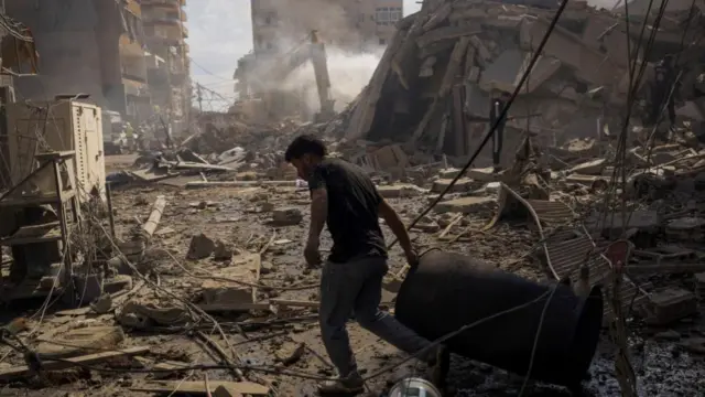 Ένας άνδρας τραβάει ένα τύμπανο στο σημείο της ισραηλινής επίθεσης στην Τύρο του Λιβάνου.