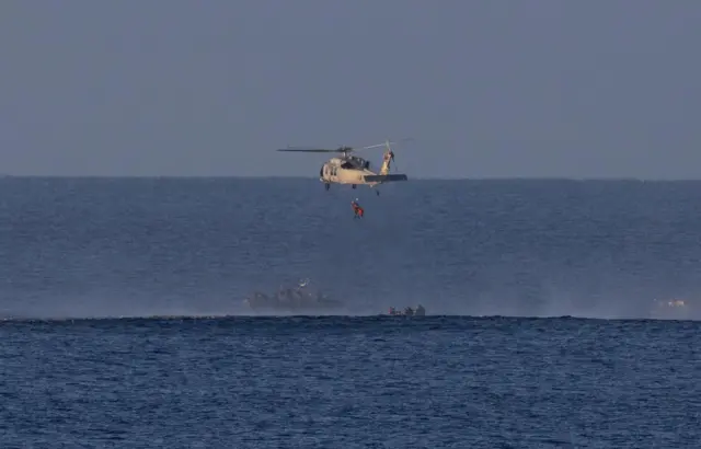 Nasa astronaut Victor Glover is seen being hoisted onto a Navy helicopter following the return of the Orion spacecraft