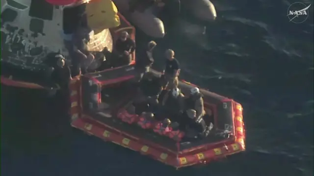 The crew of the successful Artemis II mission seen sitting on the front porch, with various rescue personnel around them.