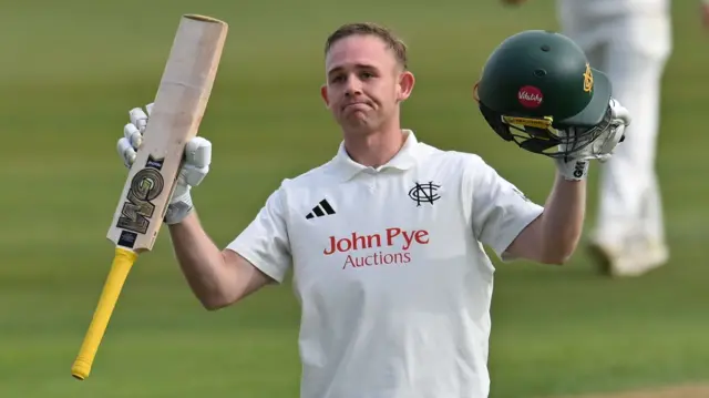 Notts' Jack Haynes raises his bat and helmet after scoring a century against Glamorgan
