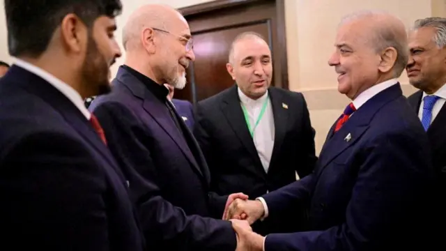 Shehbaz Sharif grasps the hands of Mohammad Bagher Ghalibaf as other senior Iranian officials stand around them.