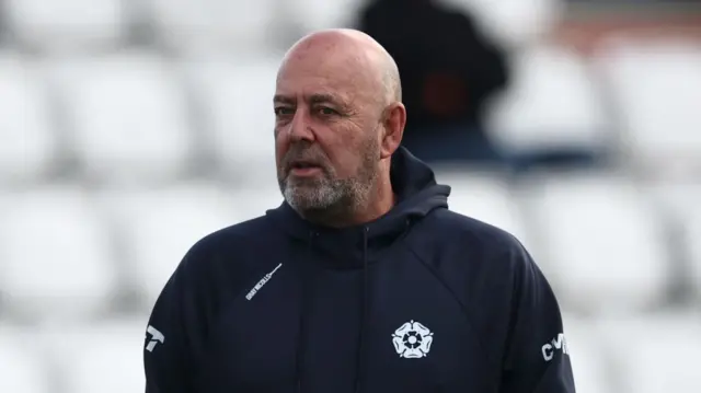 Northants coach Darren Lehmann wearing a big training coat with his hands in his pockets