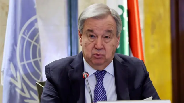 António Guterres, an older man with grey hair, in a suit and blue tie speaking into a microphone.