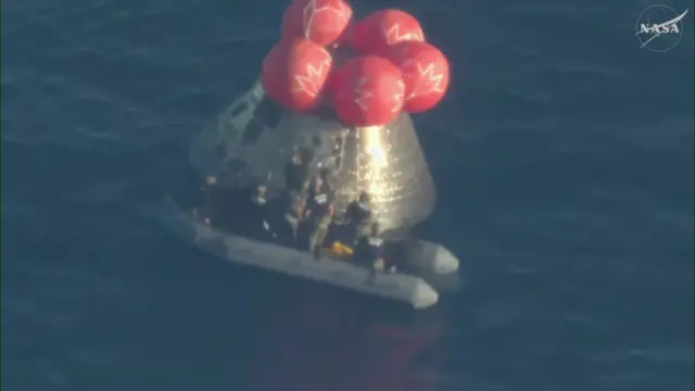 Rescue personnel seen alongside the Orion spacecraft in the Pacific Ocean