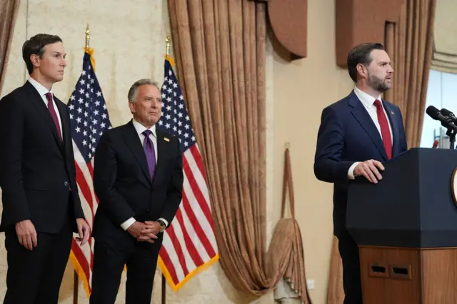 JD Vance stands at a podium, with Trump’s son-in-law White House advisor Jared Kushner and US Special Envoy to the Middle East Steve Witkoff behind him