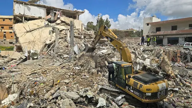 An excavator clears the rubble of destroyed buildings from the site of an Israeli strike that targeted the southern Lebanese village of Qana on April 12, 2026.